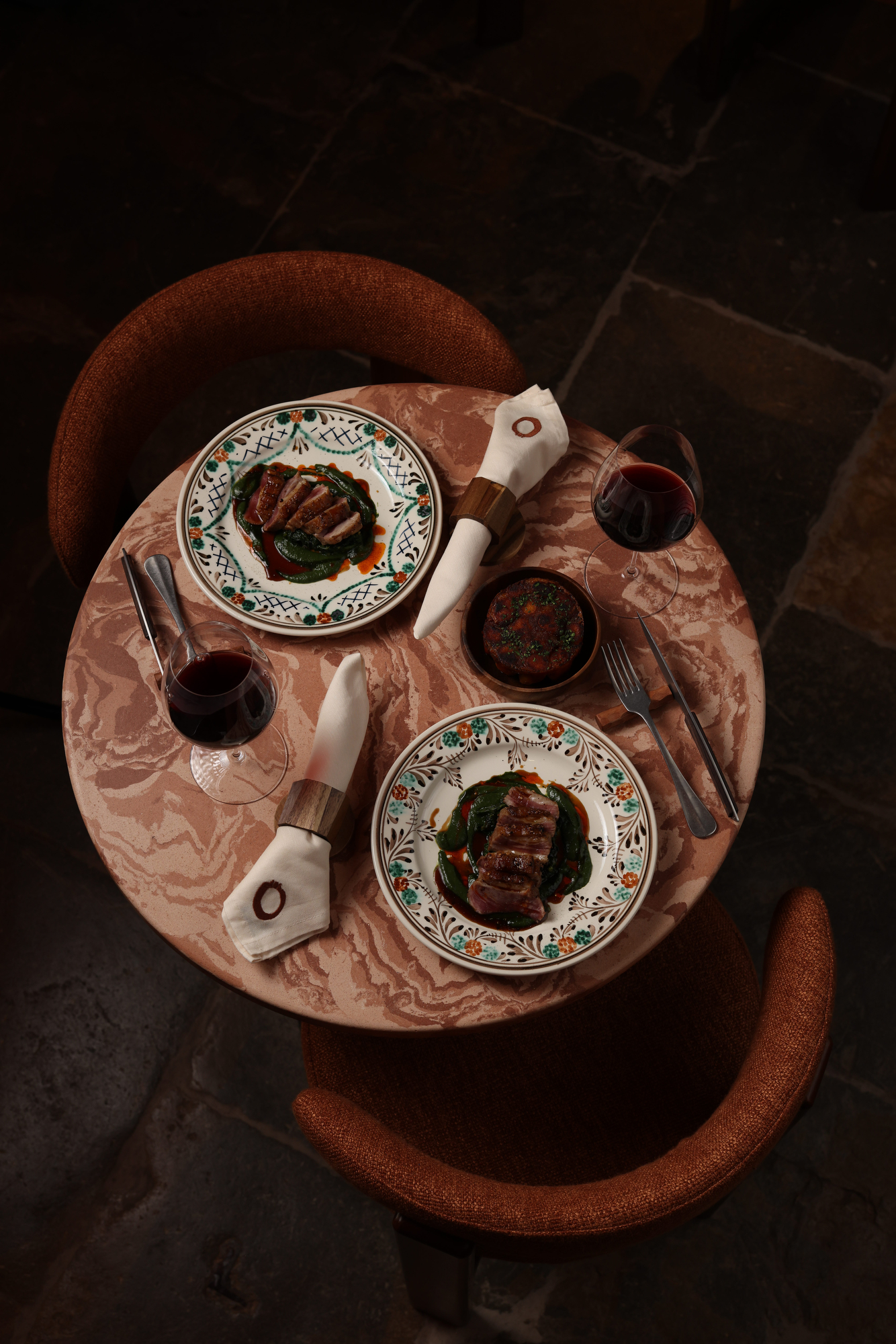 Mesa para dois com pato, vinho e louça pintada, vista de cima